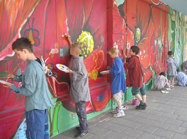 Kinderen maken een samen een muurschildering
